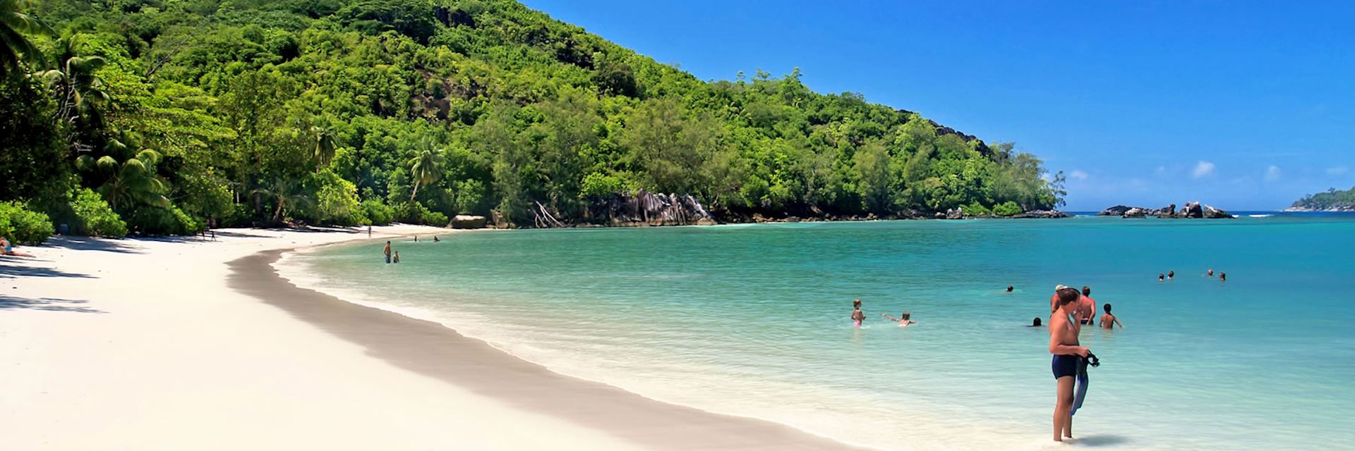 Bathers enjoy the warm, tranquil waters of a Seychelles beach 