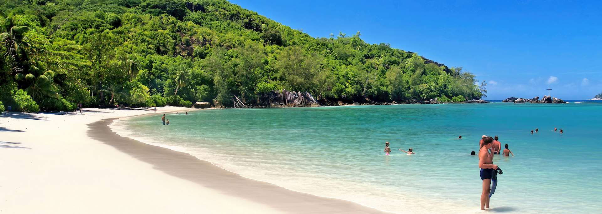 Bathers enjoy the warm, tranquil waters of a Seychelles beach