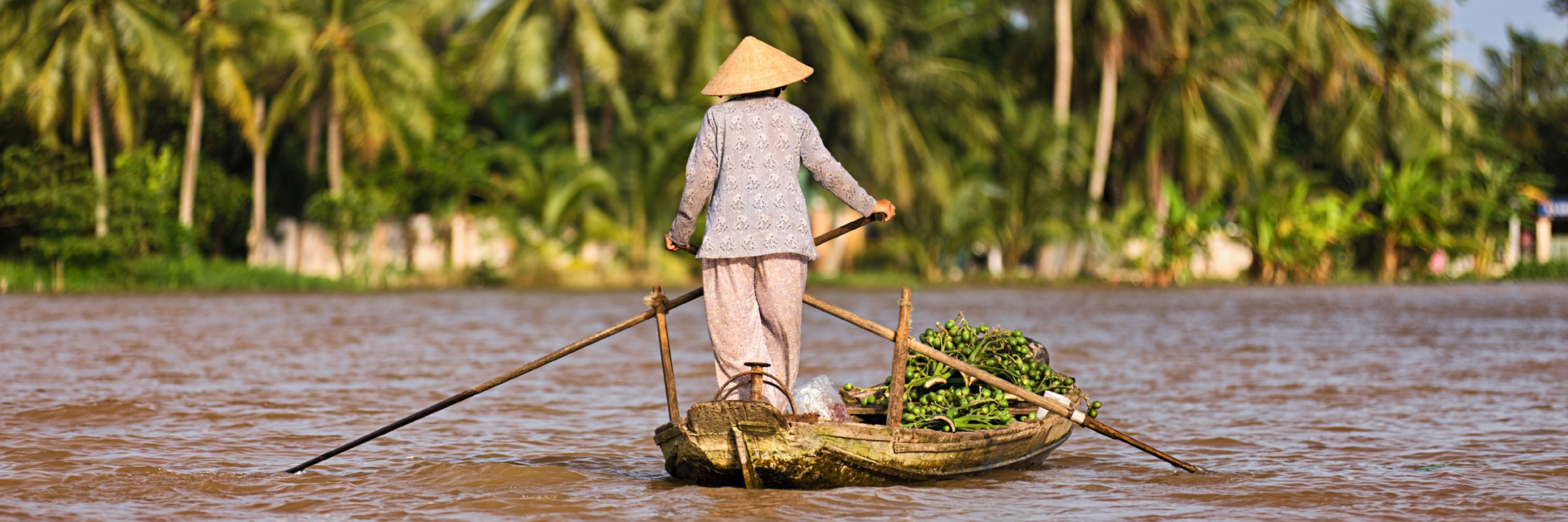 Vietnamese woman rowing a boat in the Mekong River Delta