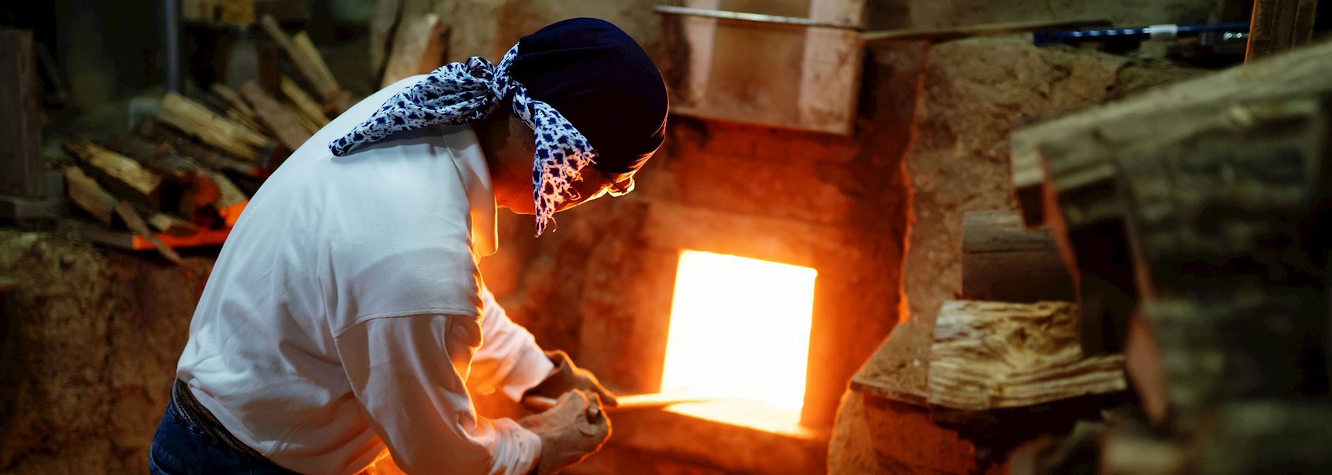 A master potter feeds wood to the kiln