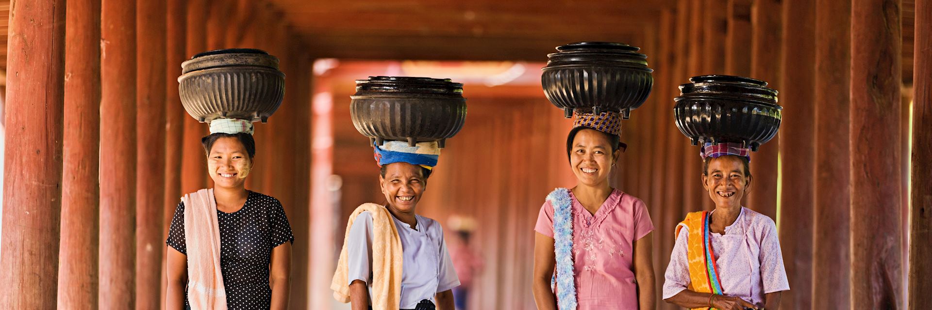 Local women carrying bowls of rice to a monastery, Myanmar