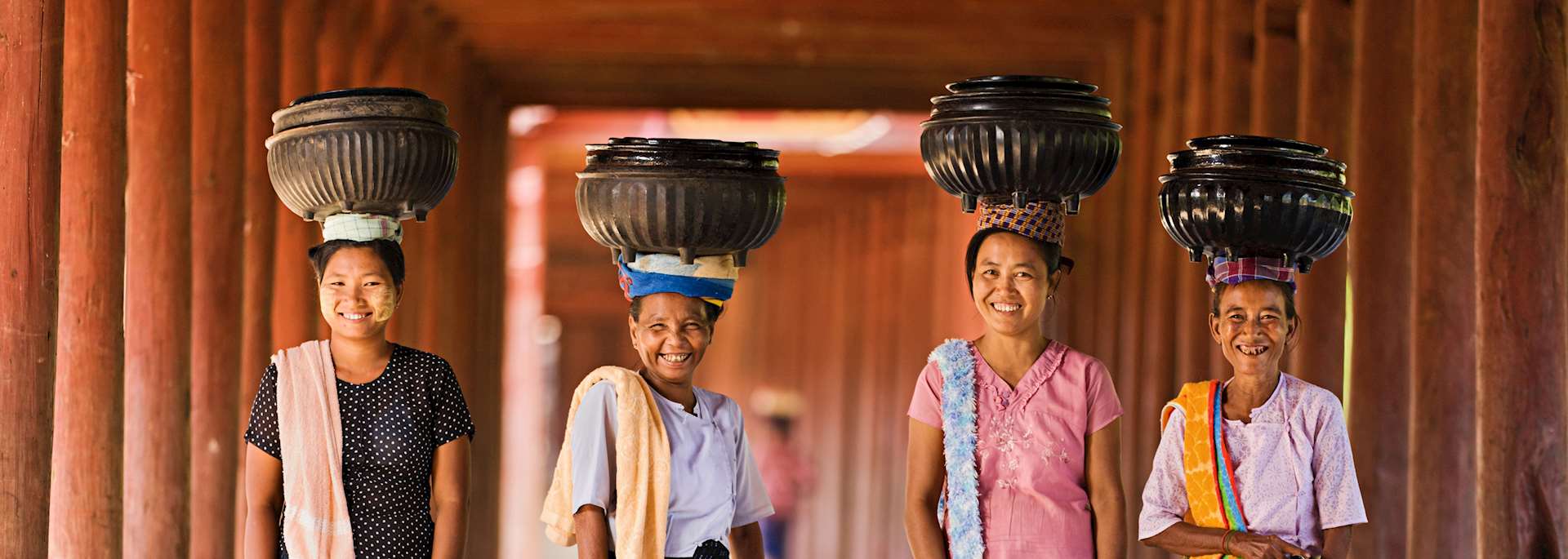 Local women carrying bowls of rice to a monastery, Myanmar