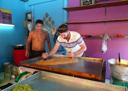 Mat helping a local make pancakes in Ayutthaya, Thailand